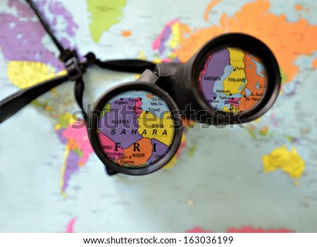 A pair of binoculars on top of a world map.  Countries highlighted in the lens.