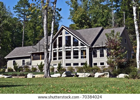 Large house with many windows and rocks in the landscape.