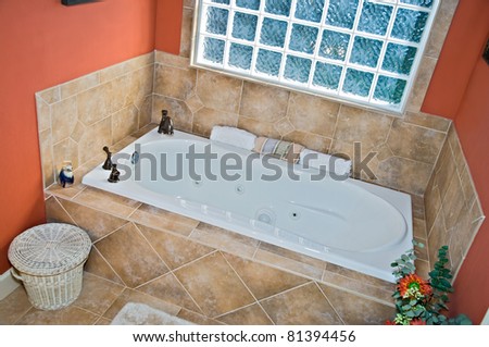 Modern colorful bathroom jacuzzi tub area with Travertine tile and bronze fixtures.