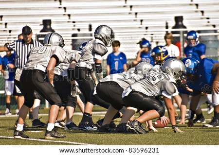 CUMMING, GA, USA - AUGUST 27: A team of 11 to 13-year-old unidentified boys face off at the scrimmage line during a football game, the Raiders vs the War Eagles, on August 27, 2011 in Cumming GA.