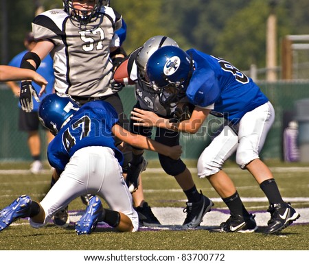 CUMMING, GA, USA - AUGUST 27: A team of 11 to 13-year-old unidentified boys during a tackle at a football game, the Raiders vs the War Eagles, on August 27, 2011 in Cumming GA.