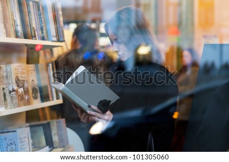 Beautiful girl reading a book in a bookstore