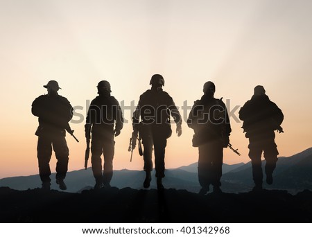 Military silhouettes of soldiers against the backdrop of sunset sky.