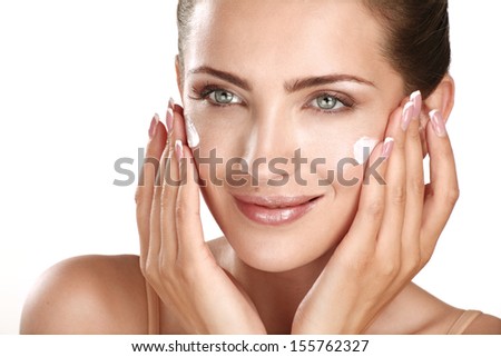 Beautiful Model Applying Cosmetic Cream Treatment On Her Face On White