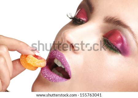 close up of a young beautiful model enjoying a sugar candy on white