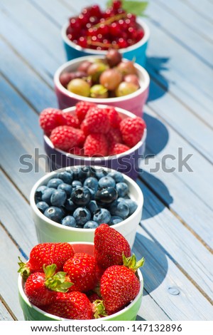 Fresh fruits in fruit bowls on wooden background