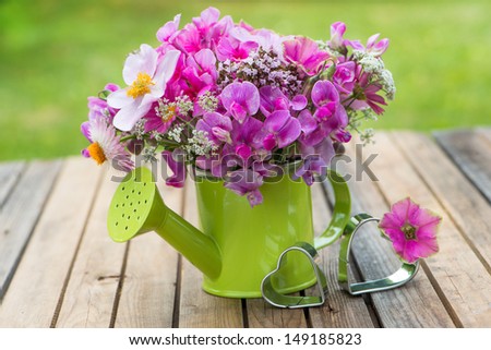 Pink garden flowers in a small watering can