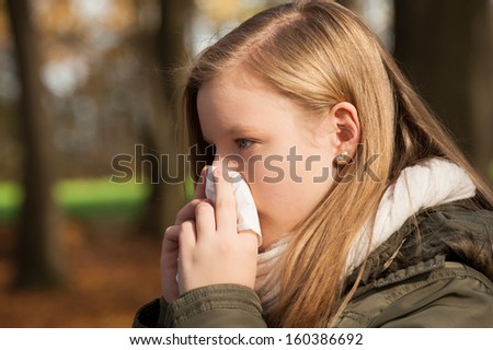 Young girl blowing her nose