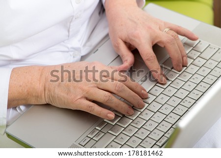 Hands of an elderly woman on computer keyboard
