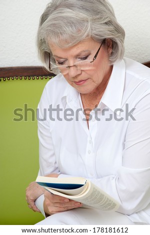 Mature woman sitting on sofa and reading a book