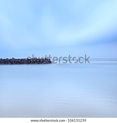 Tetrapods breakwater concrete structure; four legged armour unit beach protection against waves. Seascape sky and water in a 2 minutes long exposure photography