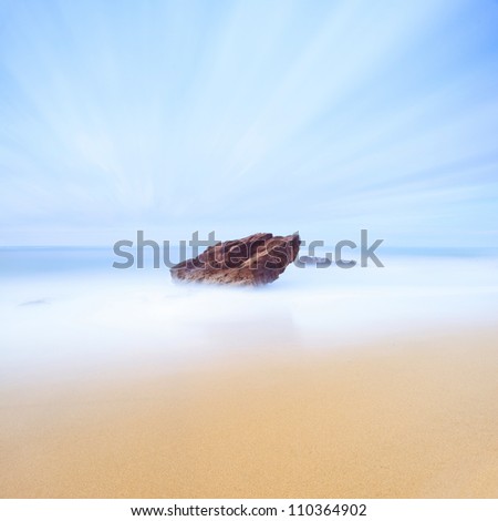 Rock, sea and gold sand seascape. Seven minutes long exposure photography. Italy