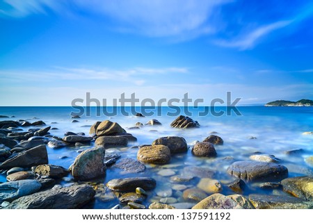 Baratti bay, rocks in a blue ocean under a clear sky on sunset. Tuscany, Italy.
