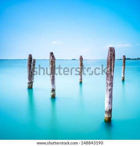Poles and soft water on Venice lagoon. Long exposure photography.