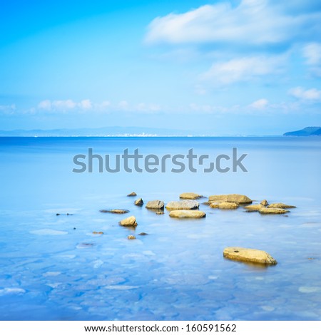 Rocks in a blue ocean in a sea bay. Long exposure photography. Punta Ala, Tuscany, Italy
