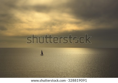 Ocean sea sunset view and black sail boat. Mediterranean sea. Tuscany, Italy