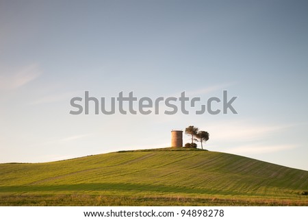 Tuscany: typical landscape with rolling hills, trees and rural tower.