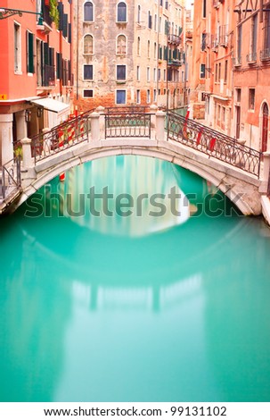 Venice, Bridge on Water Canal in a long exposure photography. Venetian small bridge and buildings in its typical architecture.