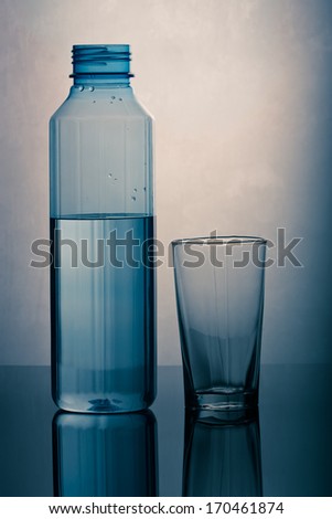 Water filled Plastic Bottle and an empty glass