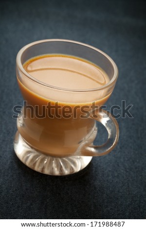 A cup of milk indian tea over jeans blue background in studio light