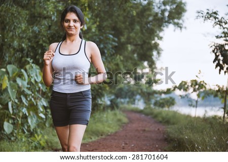 Beautiful young fit Indian girl doing running exercise or jogging vey near to lake