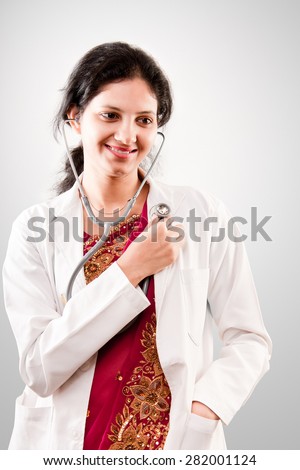 Beautiful smiling Indian lady doctor with stethoscope in sari over grey background