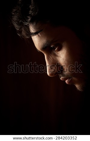 Close up portrait of a handsome indian young angry man over dark background
