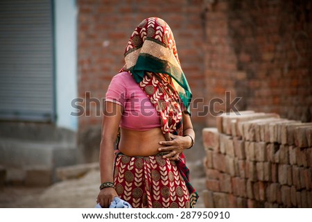 Indian villager woman in veil with dark complexion going in summer noon