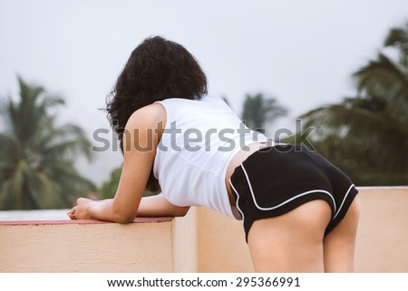 Sexy Indian woman wearing white top and black shorts, on the roof in natural lighting condition.