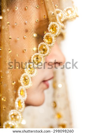Close up of a traditional Indian bride with a closed eyes, covered her face by veil.