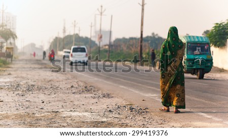 Varanasi, India - November 23, 2014: Indian woman walking on the road in indian traditional dress sari.