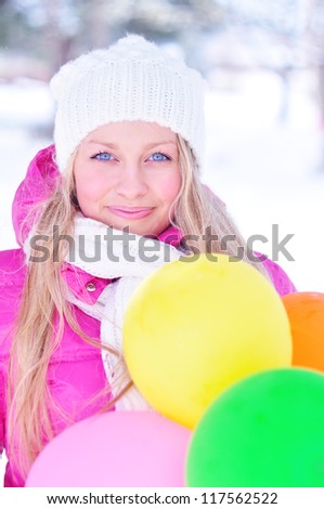 Young caucasian beautiful girl with balloons in winter outdoors at snow background