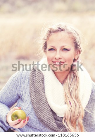 Smiling caucasian young woman holding green apple outdoors