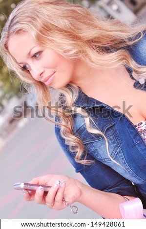 Young beautiful woman dialing phone number outdoors