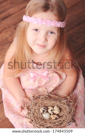 Smiling little girl sitting on the floor with bird nest