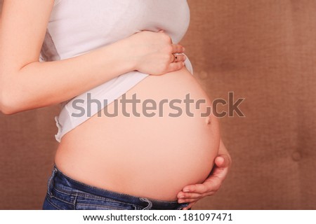 Pregnant woman holding tummy close up