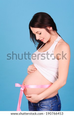 Happy pregnant woman holding belly on blue background