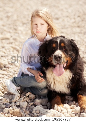 Little girl sitting with big dog outdoors