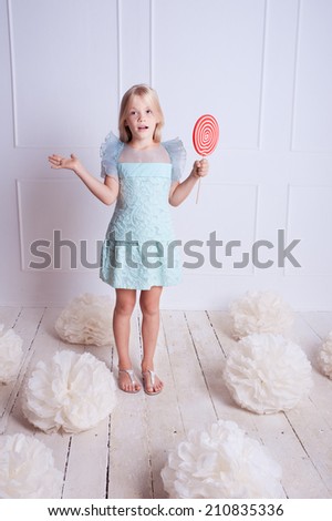 Surprised kid girl eating candy, with decorations on white