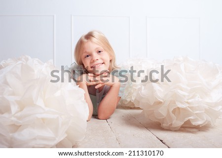 Cute kid girl lying on wooden floor with decorative clouds on white