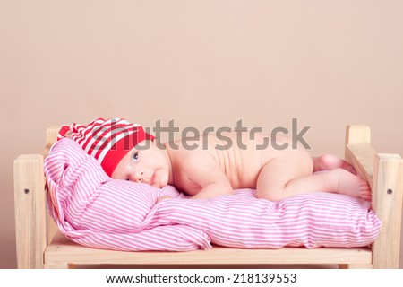 Cute baby lying in bed over beige. Childhood. Sleepy newborn child