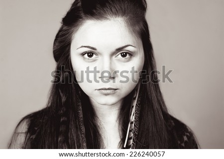 Closeup portrait of stylish young girl posing over gray. Black and white portrait