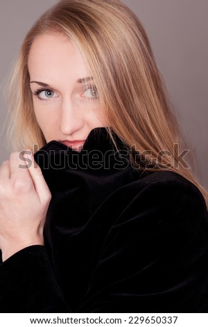 Young blonde girl 20-25 years old posing over gray. Wearing trendy black jacket. Looking at camera.