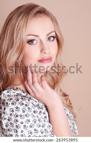 Beautiful blonde woman posing in room over beige. Long hair. Elegance. Attractive young girl.