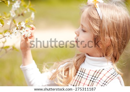 Little child girl 3-4 year old smelling cherry flower outdoors. Cute baby. Childhood.