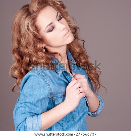 Beautiful young girl 20-24 year old wearing denim shirt over grey. Posing in room.