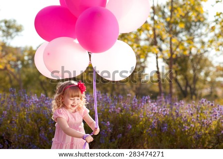 Smiling child girl 3-4 year old with pink balloons outdoors. Birthday party. Playful. Childhood. Little princess.