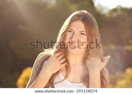 Laughing young girl 20-24 year old having fun outdoors. Looking at camera. 20s.