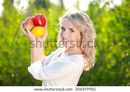 Smiling blonde girl 20-24 year old holding organic food outdoors. Posing over nature background. Looking at camera. Healthy lifestyle.