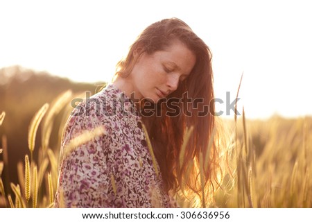 Beautiful girl 20-24 year old posing at sunset in meadow outdoors. 20s.